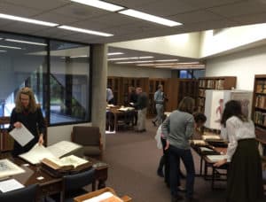 Color photograph of several people looking at books in an exhibit in the John Martin Rare Book Room at Hardin Library.