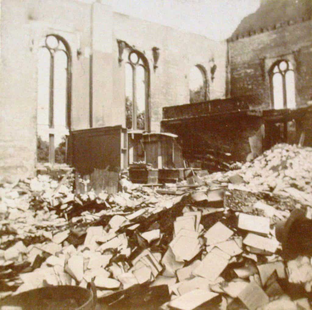 The image shows more debris after the fire. Books are scattered around the floor in piles, and it looks like there are some bookshelves standing in the back corner of the room.