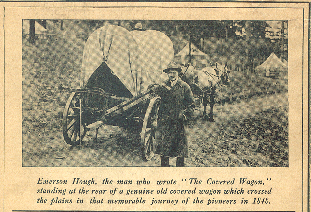 Emerson Hough, the man who wrote " The Covered Wagon, standing at the rear of a genuine old covered wagon which crossed the plains in that memorable journey of the pioneers in 1848.