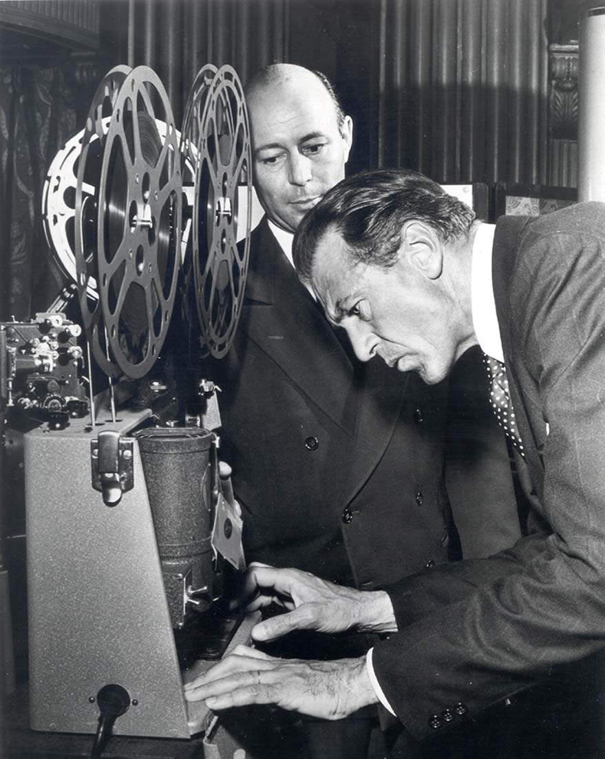 Two men examining a real-to-reel film projector