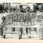 Several people hold a white banner that says 
