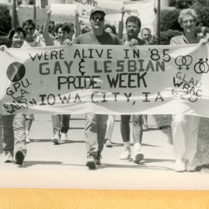 Several people hold a white banner that says 