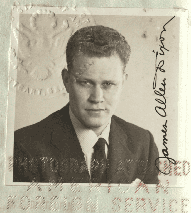 Black and white photograph of a 30-something white man pasted into a passport book. His cursive signature is present and there are stamps from the 1950s affirming the validity of the passport.