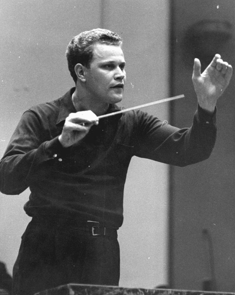 Black and white photograph of James Dixon in his 20s conducting an orchestra.