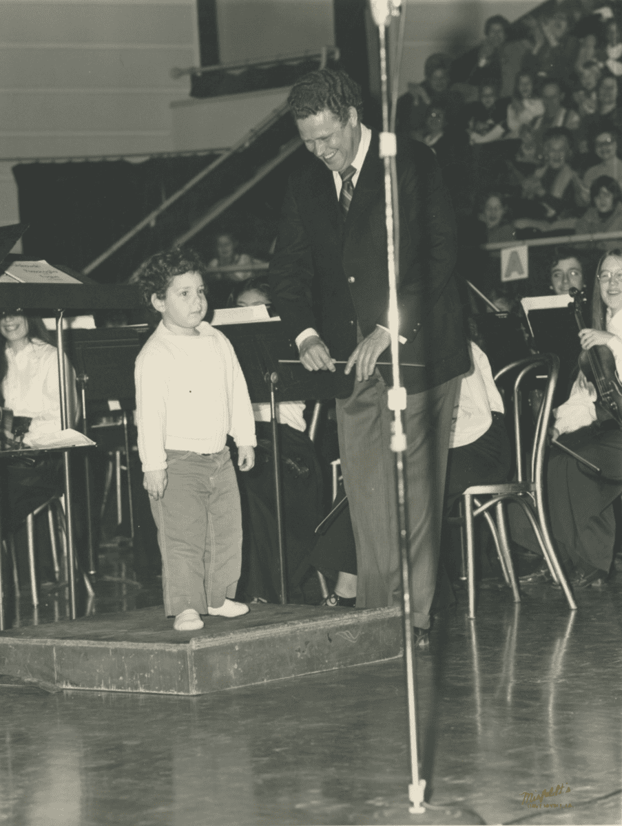 Dixon helping a young child learn about conducting at the podium.