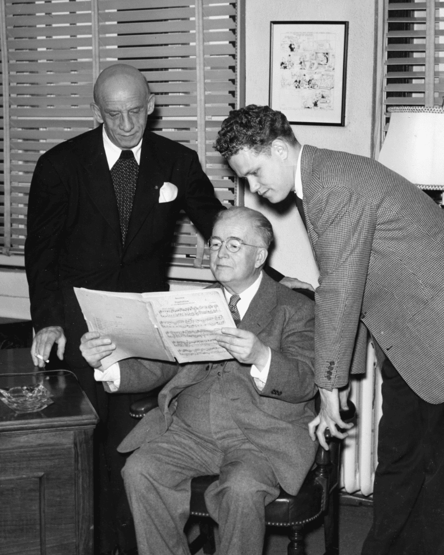 Conductor Dimitri Mitropoulos, UI School of Music Director PG Clapp, and student James Dixon look at a music score together.