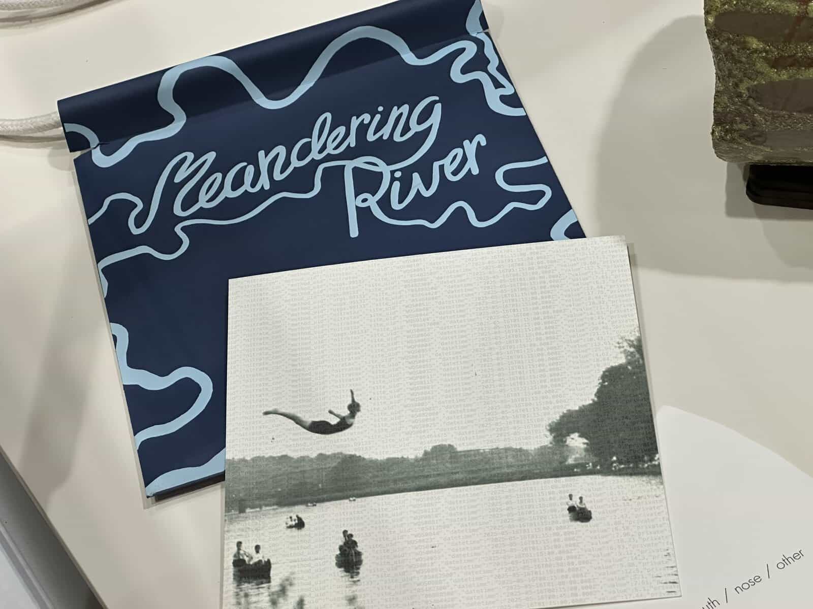 Parts of the meandering river kit, including a paper envelope made with rich blue dye and a reprint of an archival photo of students diving into and boating on the Iowa River in Iowa City.