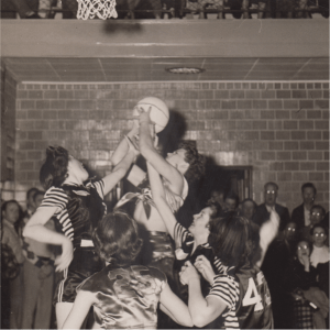 women athletes jumping for a shot in a basketball game