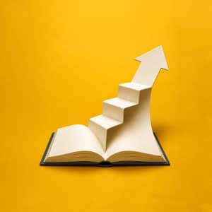 An open book transforms into ascending steps ending in an upward arrow against a gold background.